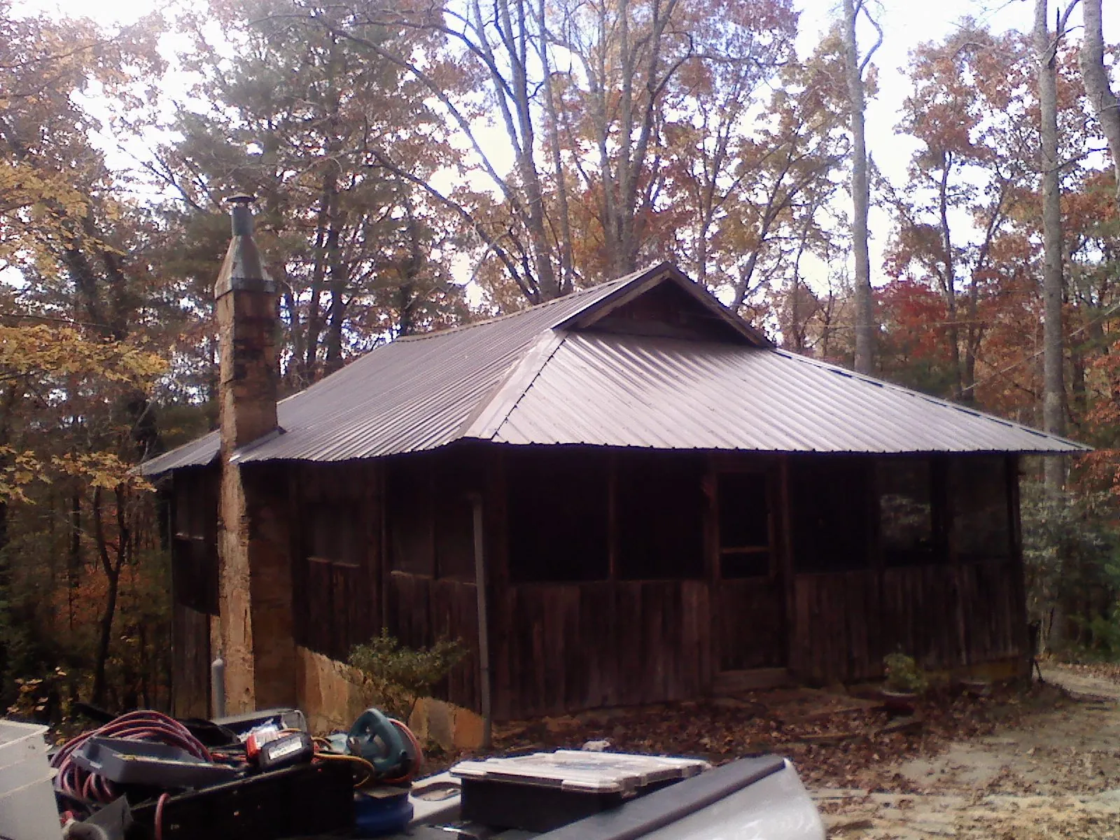 Brown metal hip roof on an old cabin with a stone chimney in Blaine