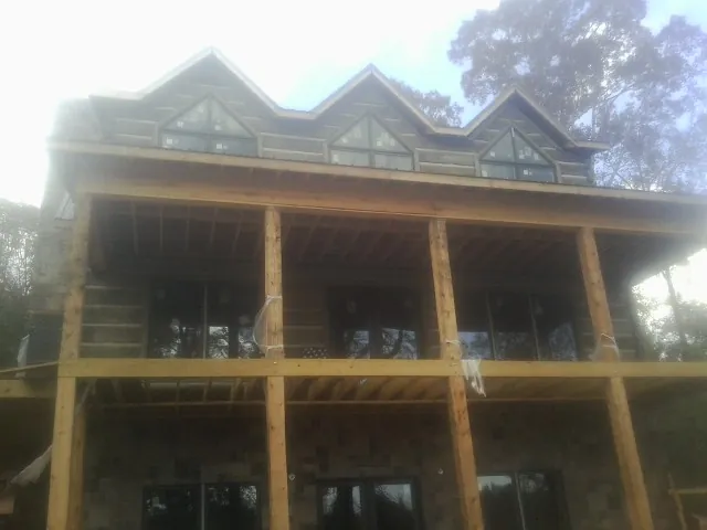 Dormers and porch framing on a large log home under construction — Roof Coating work by our crew in Blaine